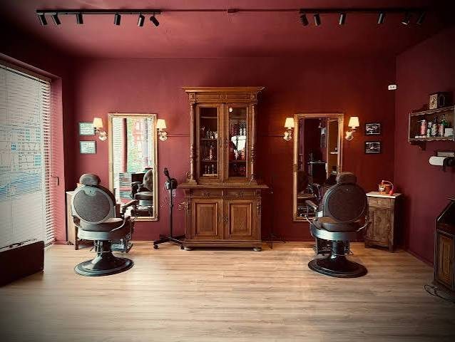 Zwei klassische Barbierstühle vor goldgerahmten Spiegeln im Salon von Edelwild Barbier