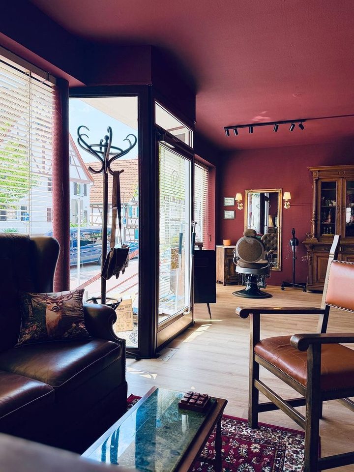 Wartebereich mit Ledersofa, Sessel und Blick in den Salon von Edelwild Barbier in Leonberg